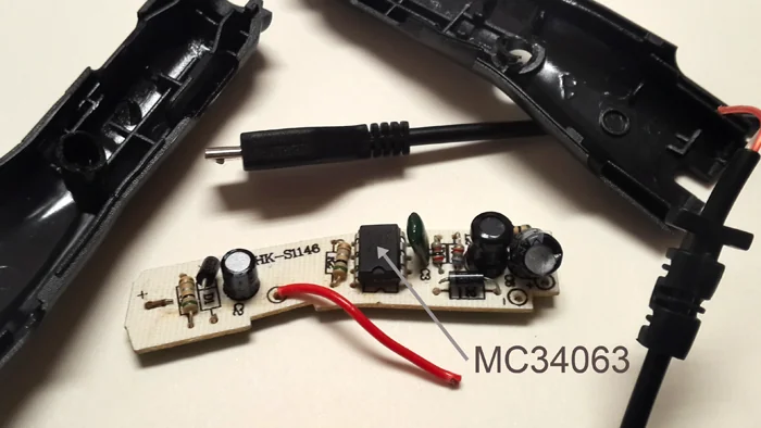 Cargador de celular de auto desarmado, con su placa de circuito y el chip MC34063 señalado