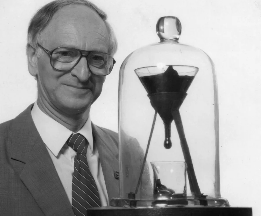 El profesor John Mainstone junto al experimento de la gota de brea de la Universidad de Queensland