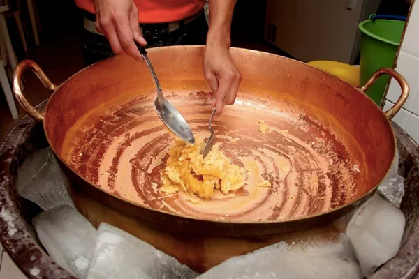 Preparación tradicional del helado de paila en una paila de cobre sobre hielo