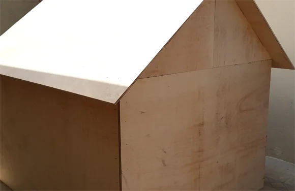 Assembled plywood playhouse with gabled roof, still unpainted