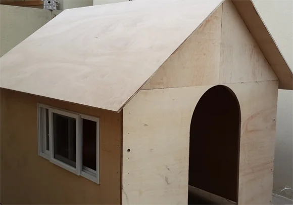 Wooden playhouse with arched doorway and sliding window installed